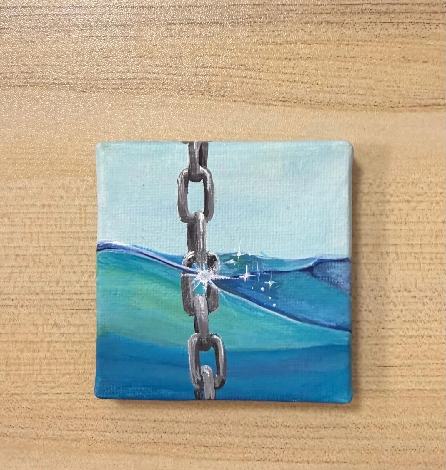 Kleine quadratische Leinwand mit gemalter Ankerkette, die ins türkise Wasser führt